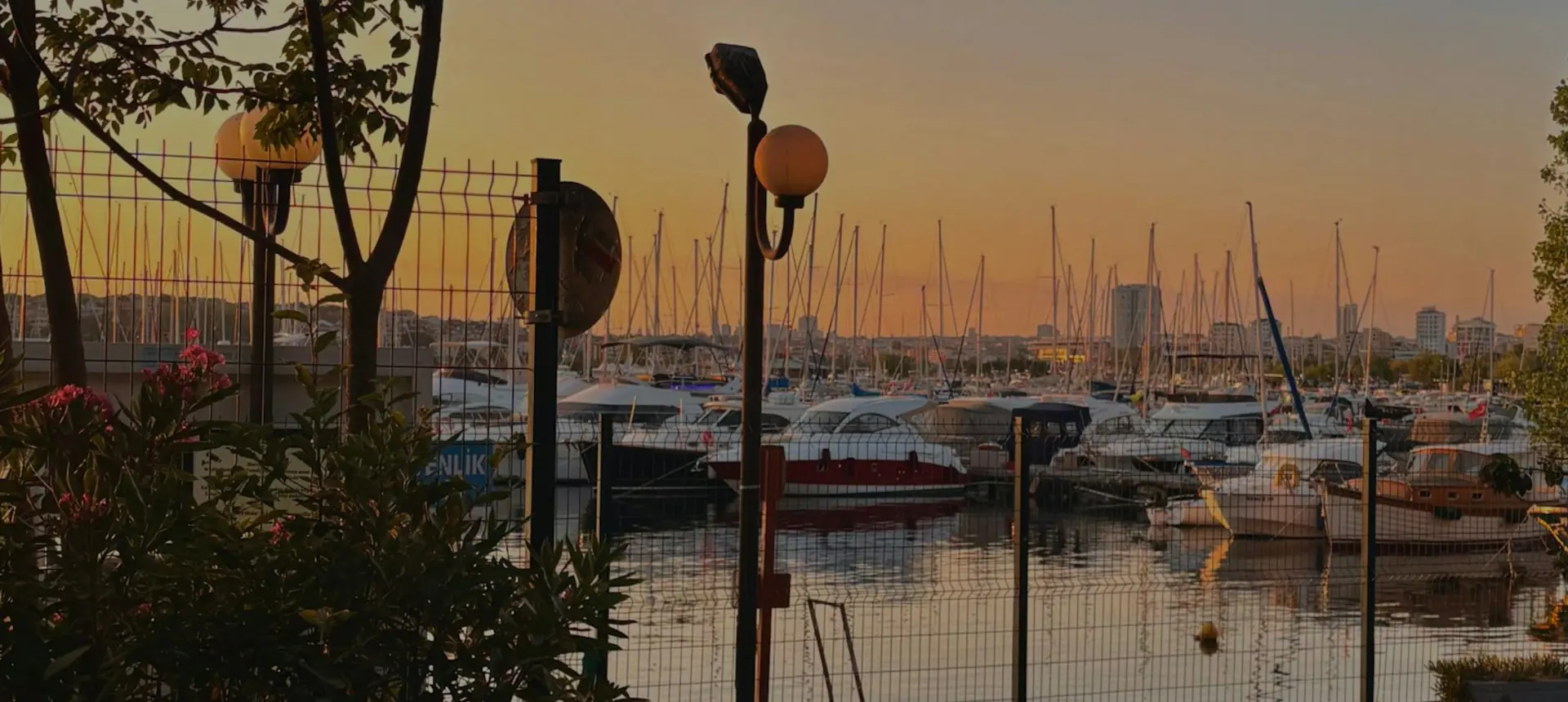 Kadıköy harbor at sunset with boats moored along the waterfront